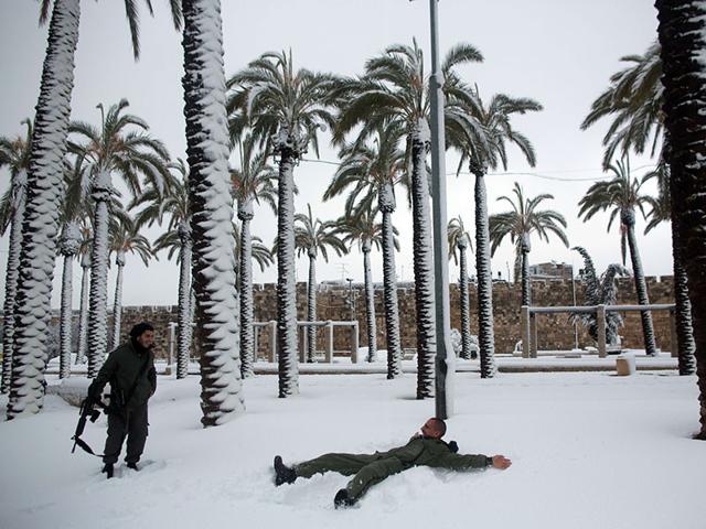 Israeli policemen play in the snow near palm trees outside Jerusalem's old cit. People in Jerusalem woke up to around 25 centimetres of snow after the second major blizzard of winter swept across the hilltop Holy City. (AFP photo)