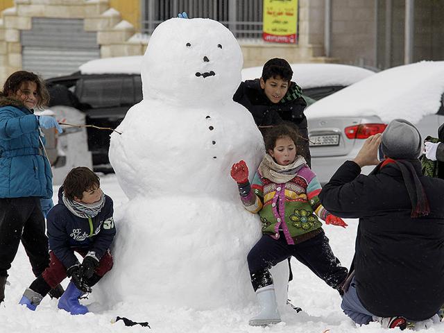 Jordanian children make a snowman in the Jordanian capital Amman. Blizzards dumped a blanket of snow over Israel, Jordan and Lebanon, with many residents urged to stay in their homes because of blocked or icy roads. (AFP photo)