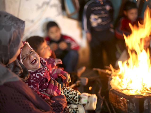 Members of a Palestinian family warm themselves by a fire at the remains of their house that witnesses said was destroyed by Israeli shelling during a 50-day war last summer, on a winter day east of Gaza City. (Reuters)