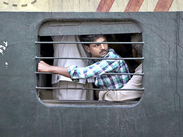 A passenger sits on the lap of another man as he travels in a crowded local train on the outskirts of Kolkata. (AP photo)
