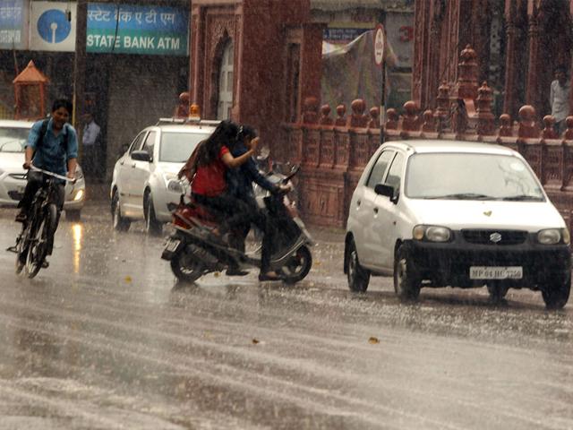 Commuters in Indore run for shelter as sudden rain lashes the city on Saturday. (Arun Mondhe/HT photo)