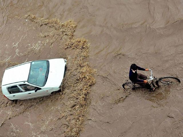 A car and cyclist move through a waterlogged road after rains in Patiala on Monday. PTI Photo