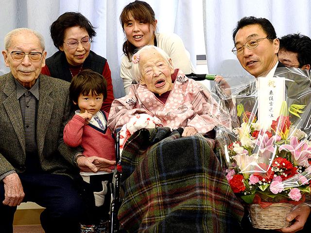 Misao-Okawa-116-center-who-is-recognized-as-the-world-s-oldest-living-person-by-Guinness-World-Records-poses-with-her-relatives-and-Ward-Mayor-Takehiro-Ogura-in-Osaka-western-Japan-ahead-of-her-birthday-AP-Photo