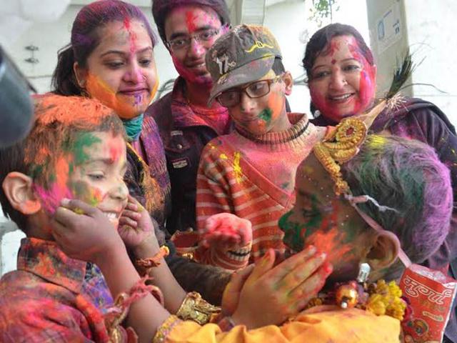 A child dressed as Lord Krishna plays with family members Holi at Durgiayana Temple in Amritsar. Sameer Sehgal/HT