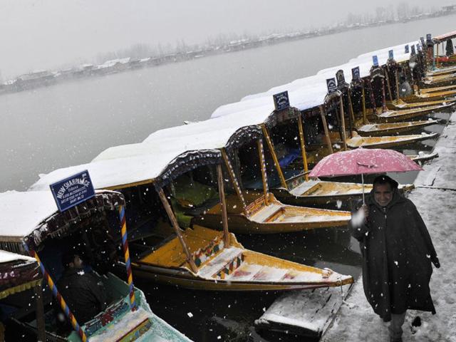 A boatman walks in front of Shikaras on the banks of Dal Lake during snowfall in Srinagar. Waseem Andrabi/HT