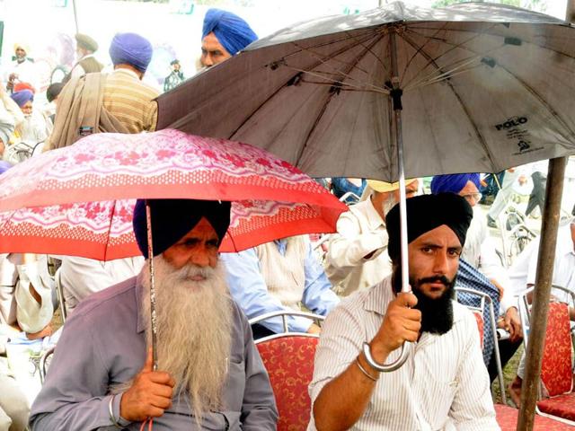 Farmers trying to protect themselves from rain during the Kisan mela at Rauni village in Patiala. Bharat Bhushan/HT