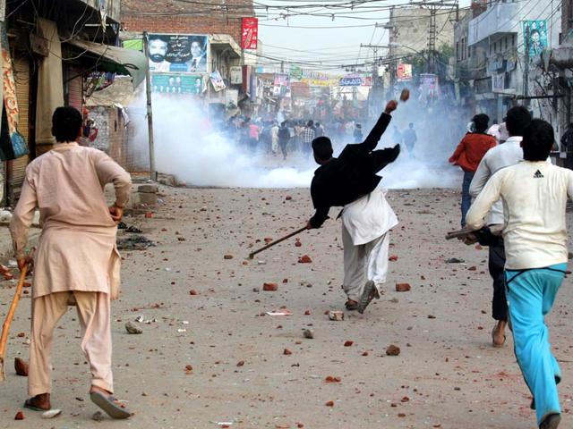 Pakistani protesters throw rocks during clashes with police to condemn suicide bombings that struck two churches in Lahore. AP Photo