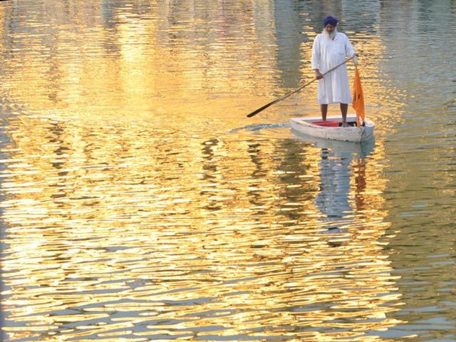 A man stands on a raft as he performs cleansing work of the Sarowar or the sacred pond of the Golden Temple in Amritsar. Sameer Sehgal/HT