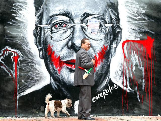 A man walks his dog next to a mural depicting former President Alvaro Uribe, in Bogota, Colombia. (AP photo)