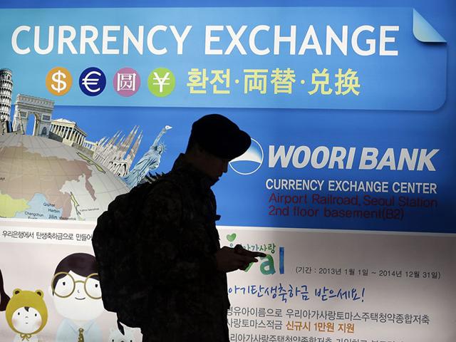 South-Korean-man-stands-in-front-of-a-poster-advertising-currency-exchange-at-a-bank-in-Seoul-South-Korea-South-Korea-one-of-America-s-closest-friends-in-Asia-announced-it-will-join-the-Asian-Infrastructure-Investment-Bank-AP-Photo