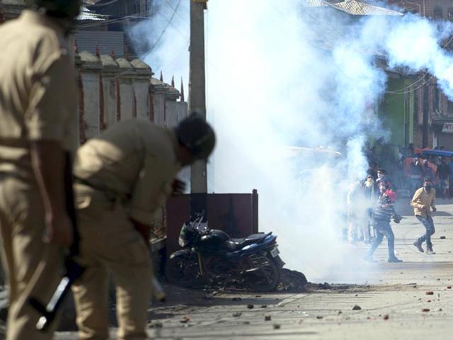 A protester throws back an exploded tear gas shell towards policemen during a protest in Srinagar, Kashmir. (AP Photo)