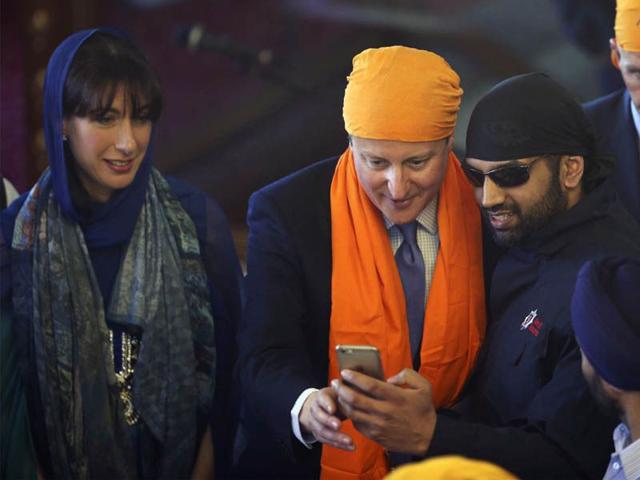 Britain's Prime Minister David Cameron, centre, poses for a selfie with a worshipper as Samantha Cameron, left, looks on as they take part in the Vaisakhi festival at Guru Nanak Darbar Gurdwara temple on Saturday.AP Britain's Prime Minister David Cameron, centre, poses for a selfie with a worshipper as Samantha Cameron, left, looks on as they take part in the Vaisakhi festival at Guru Nanak Darbar Gurdwara temple on Saturday.AP