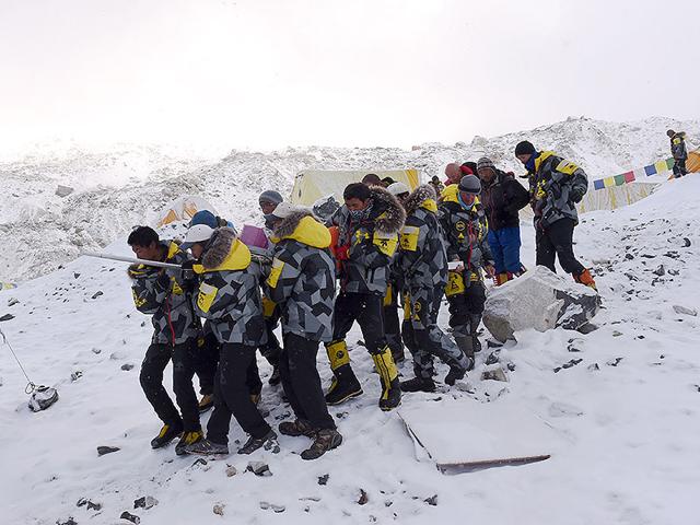 An injured person is carried by rescue members to be airlifted by rescue helicopter at Everest Base Camp. (AFP Photo)
