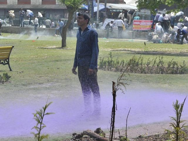 A Kashmiri daily wage government employee stands as purple-dyed water is sprayed by police personnel during a protest rally in Srinagar. Waseem Andrabi/HT