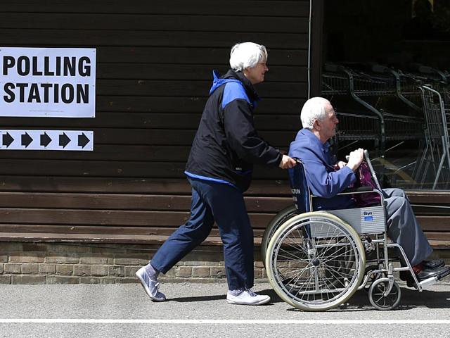 A woman pushes a wheelchair at a garden centre in Chessington, used as a polling station. (AFP Photo)