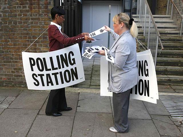 Polling station workers place signs outside a polling station in Islington. (Reuters)