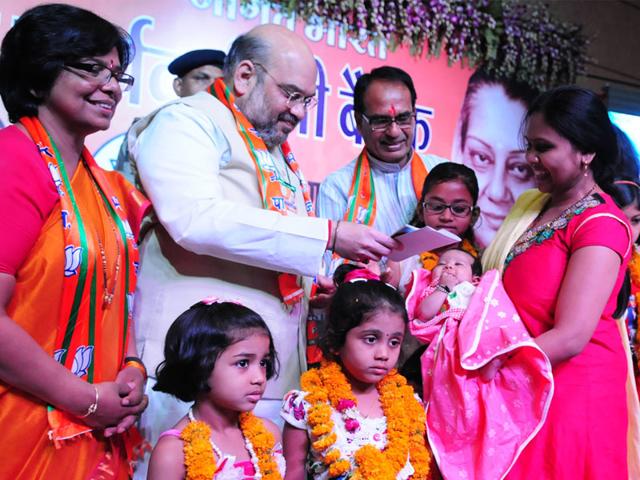 Amit Shah along with CM Shivraj Singh Chouhan hands over certificate of Sukanya Samriddhi Yoajna to a girl child, in Bhopal on Sunday. (Mujeeb Faruqui/HT photo)