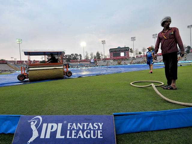 Ground staff work on the field before the rain-hit IPL 2015 match between Kings XI Punjab (KXIP) and Royal Challengers Bangalore (RCB) at Mohali on May 13. (HT Photo)