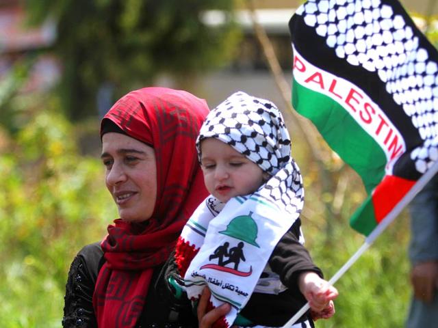 A Palestinian woman who lives in Lebanon carries her child with the Palestinian flag during a protest marking the 'Nakba'. (AP Photo)