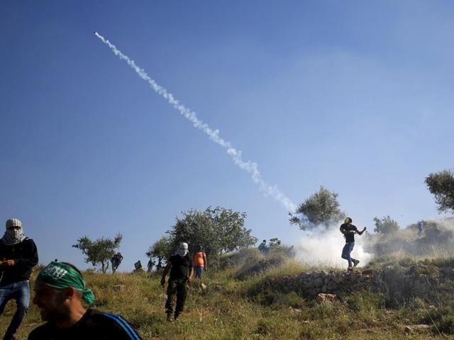 A Palestinian protester throws a tear gas canister fired by Israeli troops during clashes following a rally marking the 'Nakba' near Israel's Ofer Prison near the West Bank city of Ramallah. (Reuters)