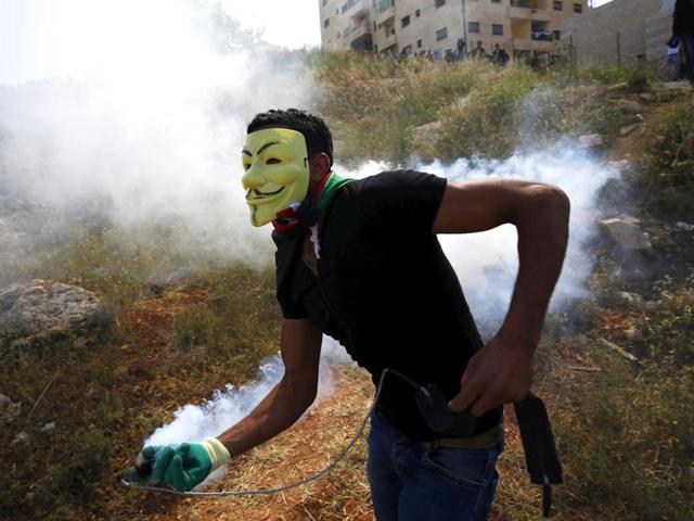 A Palestinian protester with a tear gas canister fired by Israeli troops during clashes following a rally marking the 'Nakba' near Israel's Ofer Prison near the West Bank city of Ramallah. (Reuters)