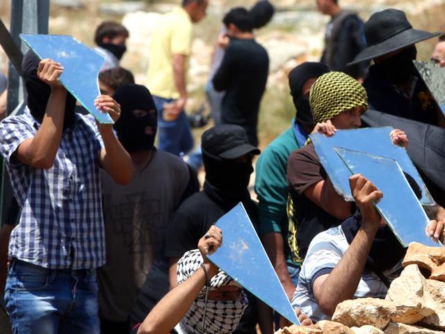 Palestinian protesters carry parts of a broken mirror during clashes with Israeli forces following a demonstration to mark the 67th anniversary of the "Nakba" on May 15, 2015, in the village of Kfar Qaddum, near Nablus, in the occupied West Bank. (AFP Photo)