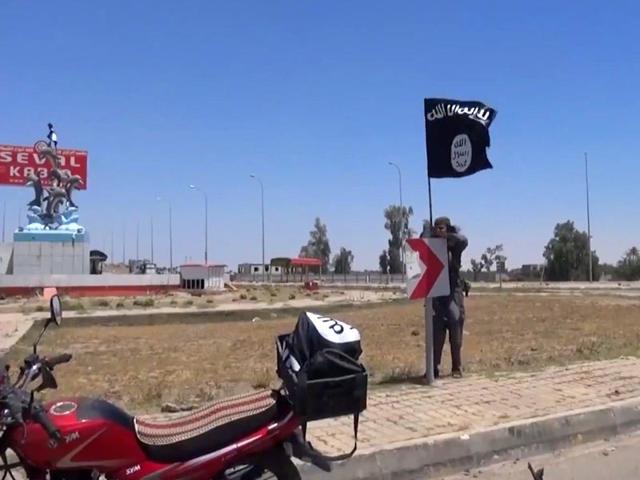 An-image-grab-taken-from-a-video-uploaded-on-May-18-2015-by-Aamaq-News-Agency-a-Youtube-channel-which-posts-videos-from-areas-under-the-Islamic-State-IS-group-s-control-allegedly-shows-an-IS-fighter-hanging-a-flag-of-the-group-in-a-street-of-Ramadi-AFP-Photo