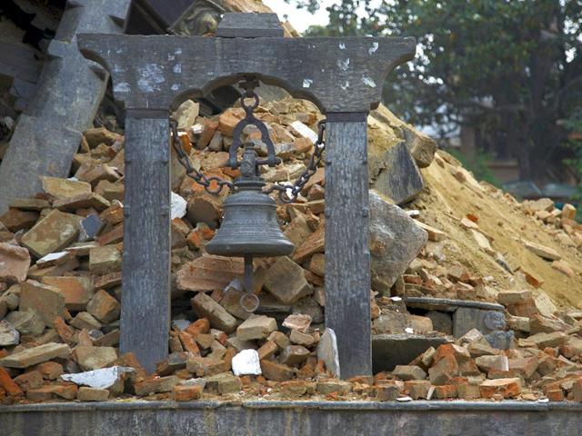 A-man-walks-past-a-damaged-house-supported-by-wooden-beams-in-Bhaktapur-Nepal-AP-Photo