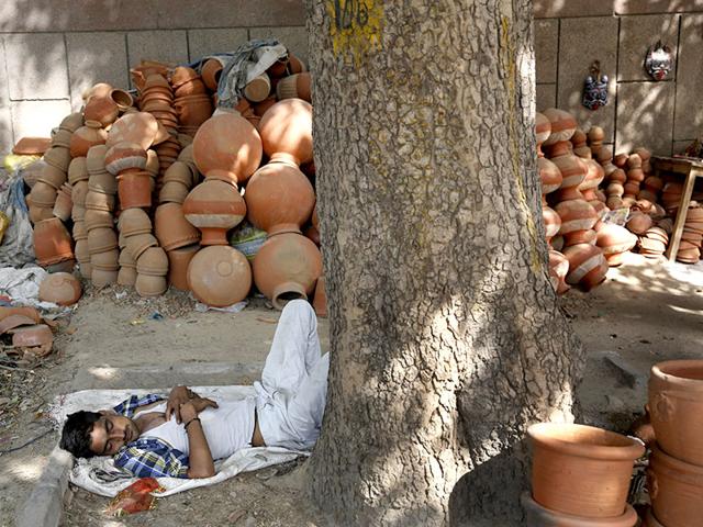 A vendor sleeps near earthen pots in the scorching heat of the Indian Capital. (AP Photo)