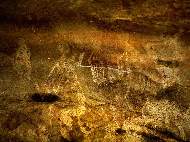 A ritual sacrifice is in progress, with two figures holding up a stick on which some sort of animal is impaled. Note the stylised decorations on the animal’s body! 
