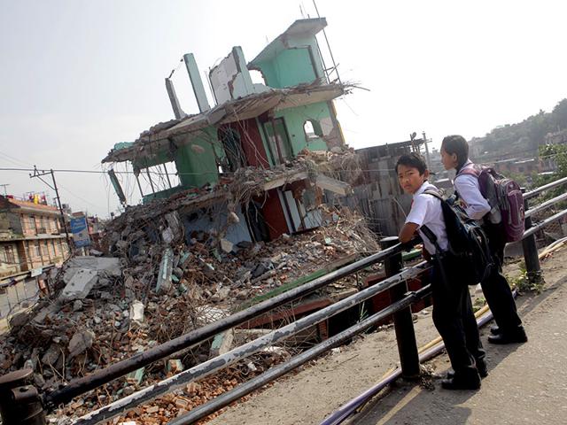 Students wait for their school bus in front of a collapsed house as thousands of schools across the districts worst hit by two major earthquakes in Nepal reopened on Sunday, in Kathmandu. With most school buildings damaged or unsafe, the education ministry ordered that classes be held in temporary classrooms. According to a Unicef statement, 32,000 classrooms were destroyed and 15,352 classrooms were damaged after the two major earthquakes in Nepal. (AP Photo)