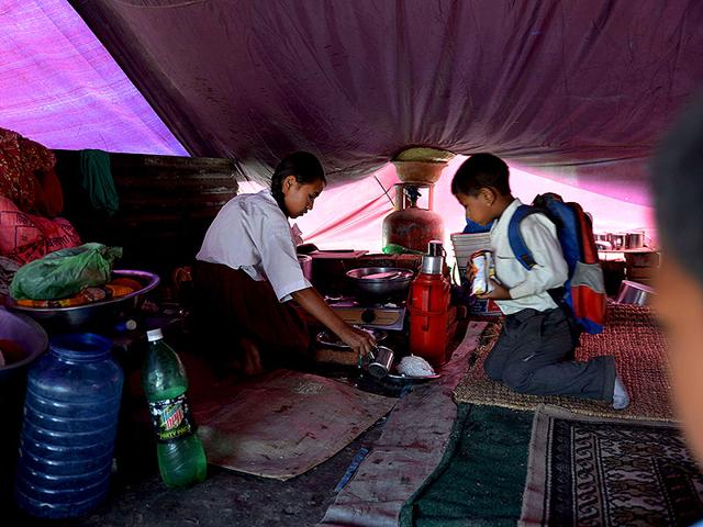 Nepalese schoolgirl Ankita Kapali (L), 11, prepares food before leaving for school in Bhaktapur in Bhaktapur on the outskirts of Kathmandu. Schools are reopened in Nepal on Sunday following a devastating earthquake on April 25 that killed over 8,600 people, and damaged nearly 8,000 schools and 30,000 classrooms. (AFP Photo)