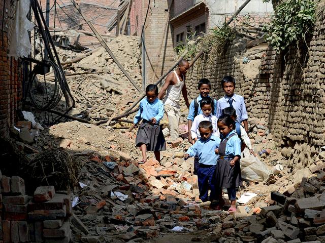 Nepalese students walk past damaged buildings to school in Bhaktapur on the outskirts of Kathmandu. (AFP Photo)