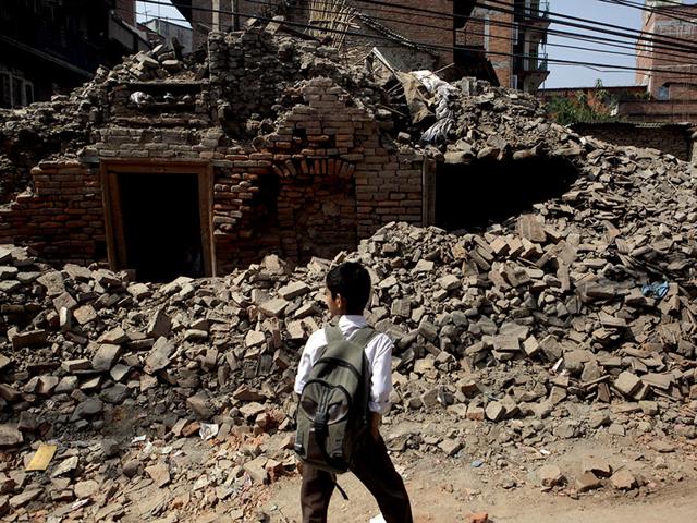 A Nepalese boy walks past a collapsed building close to his school. (AP Photo)