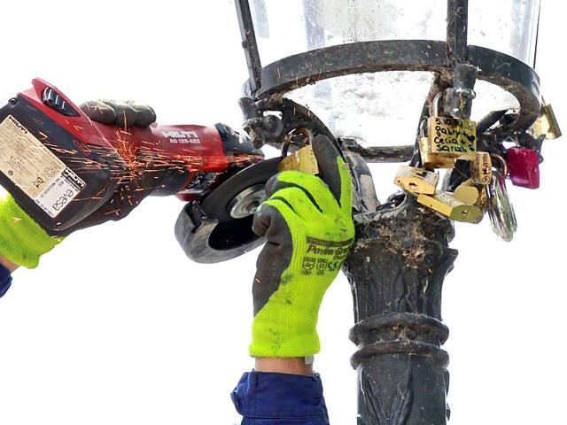 A Paris city employee uses a grinder to cut locks from a street lamp on the famed Pont des Arts bridge in Paris. City authorities are taking down thousands of padlocks affixed to the famed bridge. The city council says the locks, usually hung by couples to express eternal love, cause long-term damage to Paris heritage and sometimes pose a security risk. Last summer a chunk of fencing fell off under their weight. (AP Photo)