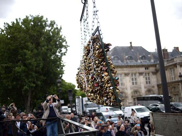 People take photographs as workers remove panels bearing 'love padlocks' attached on the railings of the Pont des Arts bridge in Paris. Started by tourists in Paris in 2008, the 'love locks' ritual, which also spread in the early 2000s to cities including New York, Seoul and London, has resulted in the transformation of several bridges: every inch of their railings is now covered with clunky brass padlocks. (AFP Photo)