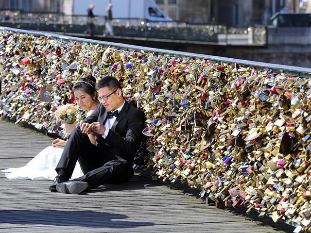 A file photo shows a newly wed couple resting on the Pont des Arts in Paris, France. The pedestrian bridge has become a shrine for amorous tourists and Parisians alike, who seek to immortalise their love by leaving an initialled padlock attached to its metallic grid railings. (AP Photo)