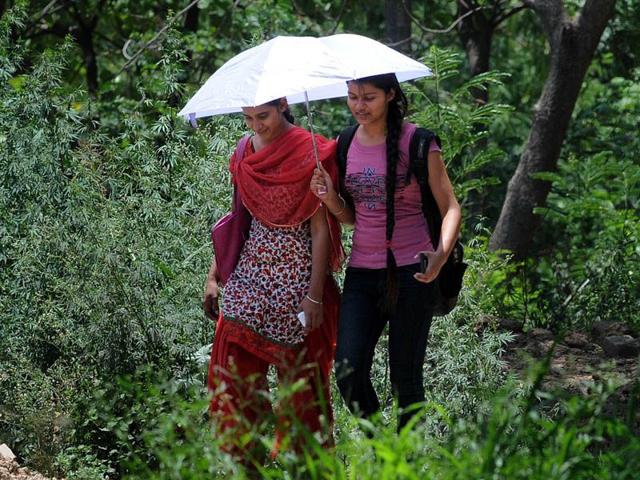 Girls trying to shield herself using umbrella to protect themselves from scorching heat at Sec-42 in Chandigarh. Gurminder Singh/HT