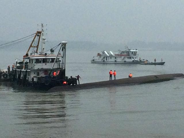 Rescue workers stand on the capsized ship, center, on the Yangtze River in central China's Hubei province. (AP photo)