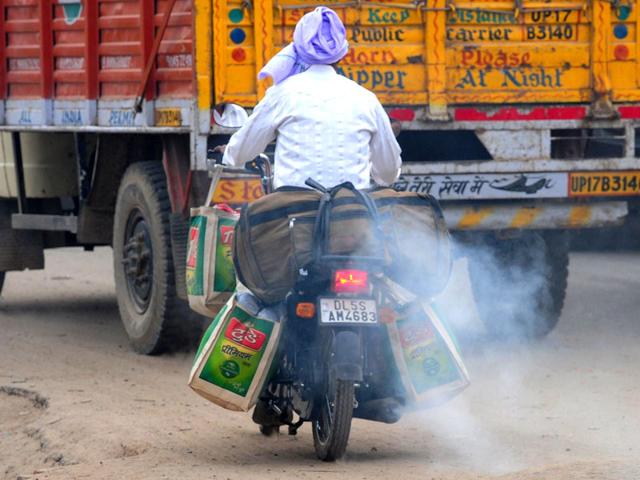 A motorcyclist rides with smoke belching from his machine in New Delhi. AFP Photo