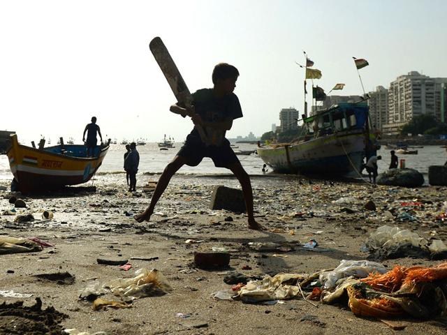 A boy plays cricket on a beach strewn with plastic garbage in Mumbai. AFP Photo