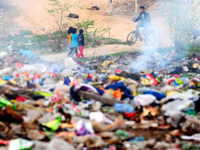 Children walk past a pile of burning garbage beside a road in Faridabad on the outskirts of New Delhi. AFP Photo