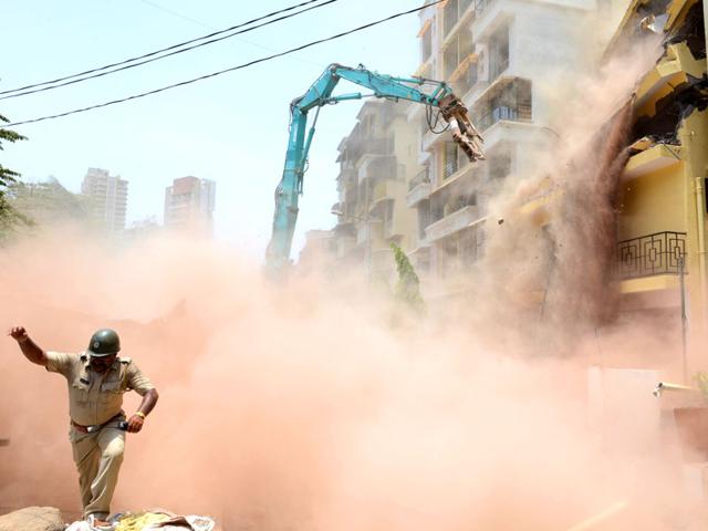 A policeman runs for cover during a demolition drive by NMMC and CIDCO at Nerul's Sector 20 in Navi Mumbai. (Photo: Bachchan Kumar)
