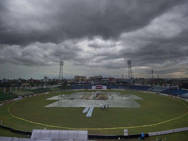 Ground staff cover the playing field during the rain-interrupted Test between Bangladesh and India at Fatullah on June 11, 2015. (AFP Photo)