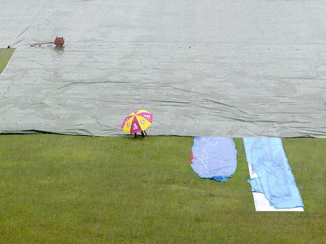 Ground staff cross the covered field as rain interrupts play during the one-off Test match between Bangladesh and India at Fatullah on June 13, 2015. (AFP Photo)