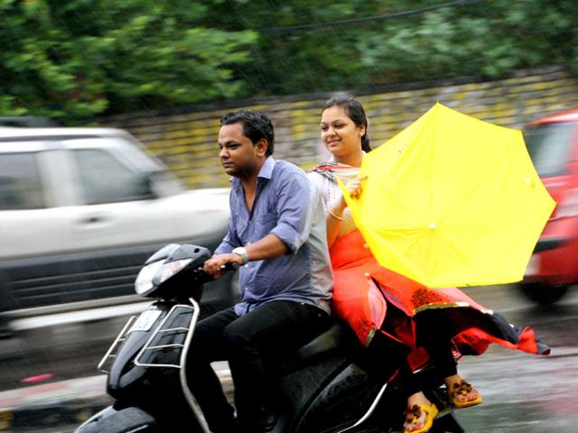 Commuters try to cope with thundershowers which lashed Rohtak town. (Manoj Dhaka/ HT Photo)