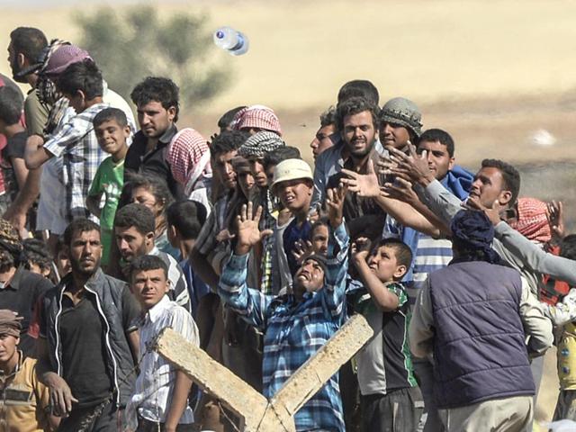 Syrian refugees near the Syrian town of Tal Abyad try to grab bottles of water thrown from the Turkish side of the border (AFP Photo)