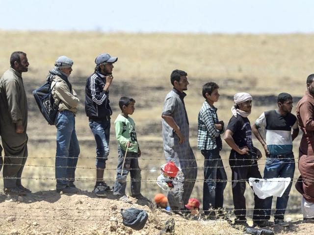 Syrian refugees wait near the Turkish border in Akcakale in the Sanliurfa province not far from the Syrian border town of Tal Abyad (AFP Photo)