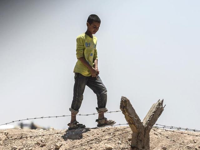 In a picture taken from Akcakale in Turkey, a Syrian boy walks at the Turkish border near the Syrian town of Tal Abyad (AFP Photo)