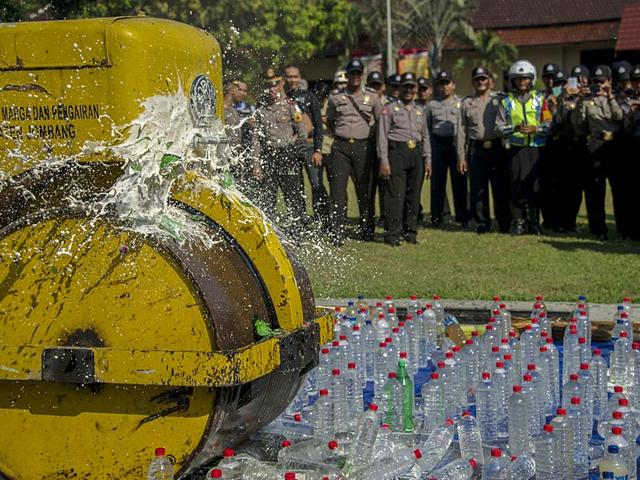 Indonesian police destroy bottles of alcohol at a police station ahead of the holy Muslim month of Ramadan in Jombang, East Java (AFP Photo)